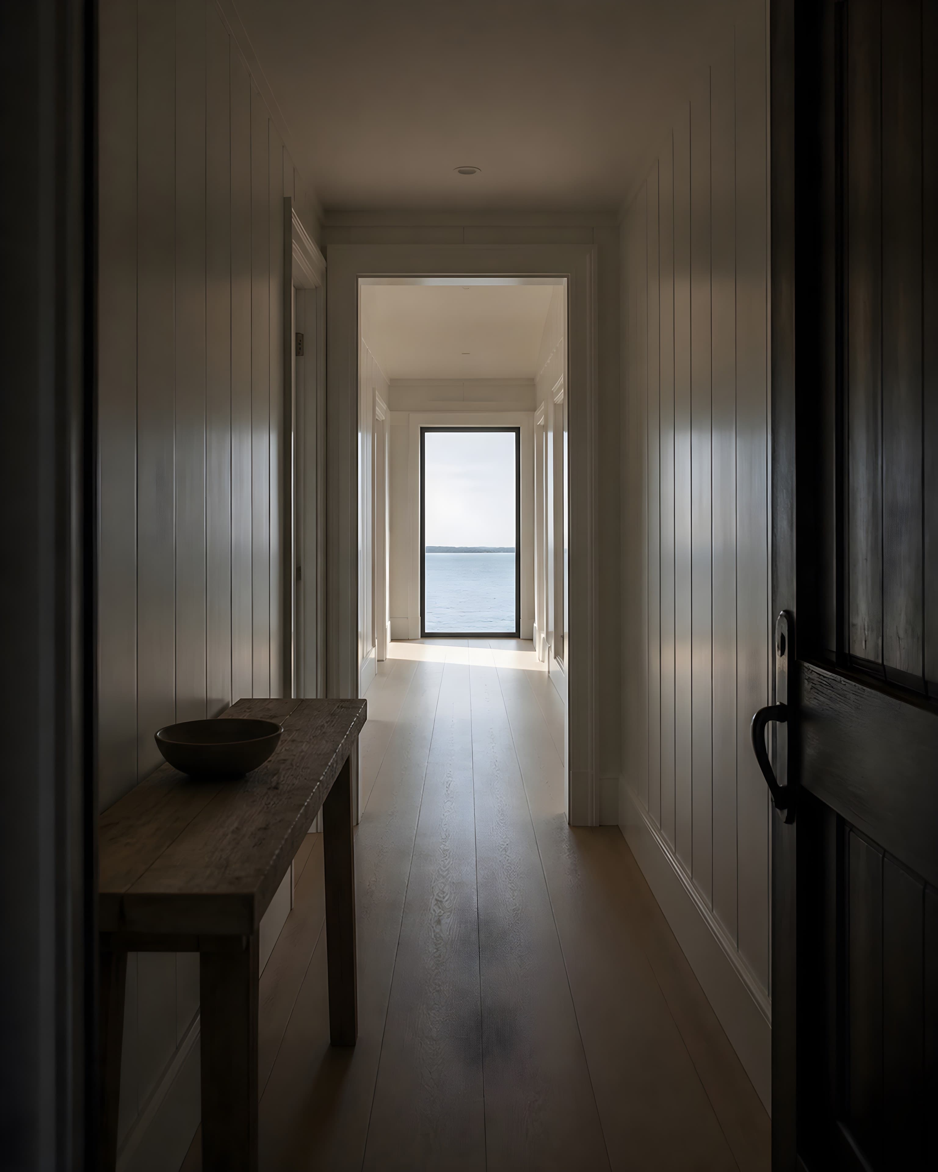 View from inside the front door through the entry hall to a full-height window filled with bay water